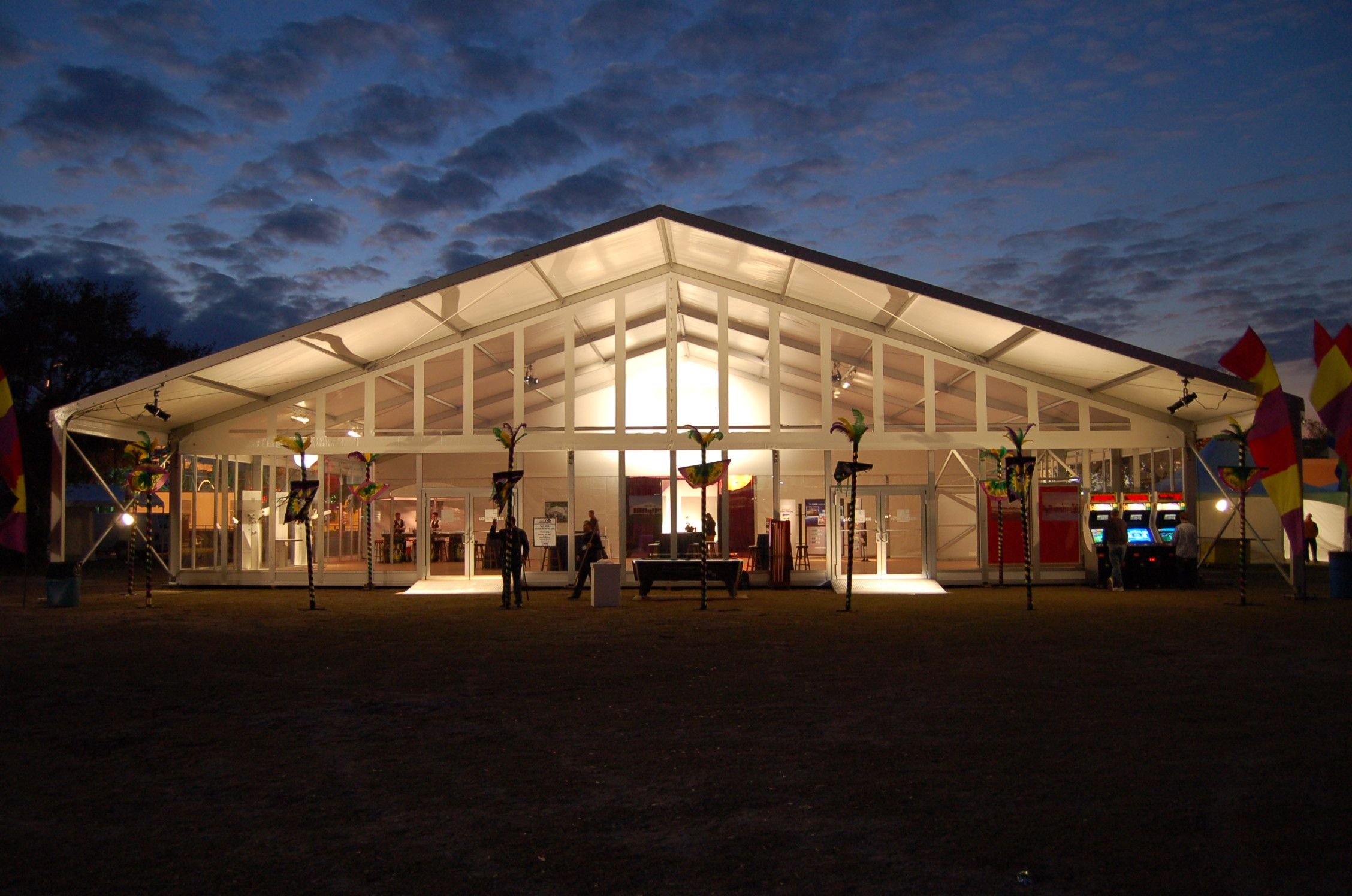 Illuminated large A-frame event tent featuring a full glass wall facade and spacious interior for corporate or public festivals.