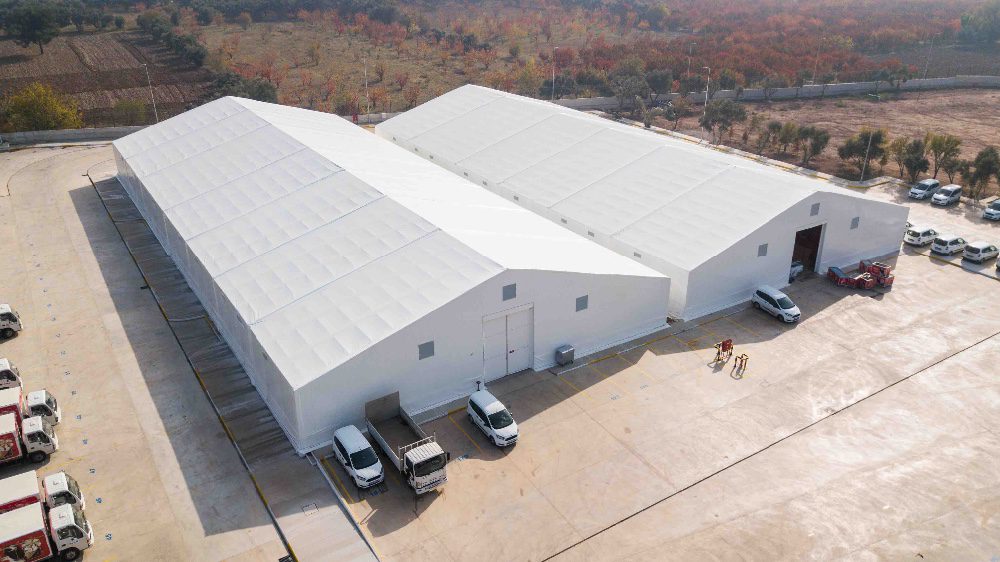 Aerial view of heavy-duty industrial warehouse tents featuring solid hard walls and large cargo doors for secure logistics storage.