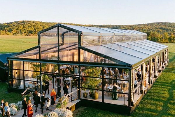 Black aluminum frame Atrium tent structure featuring glass walls and transparent roof panels hosting a luxury outdoor event.